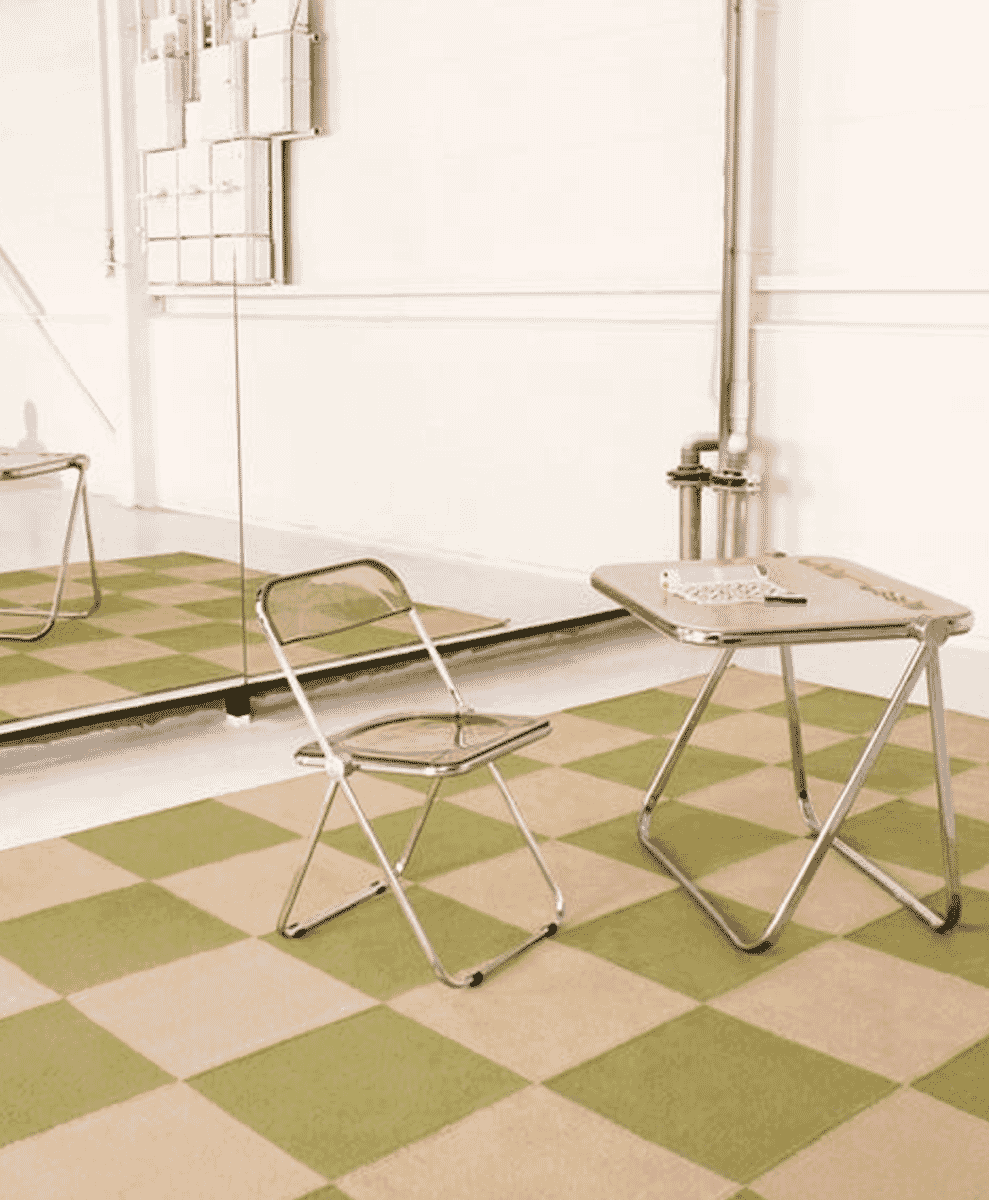 A minimalist room with green and beige checkered flooring and chrome folding furniture.