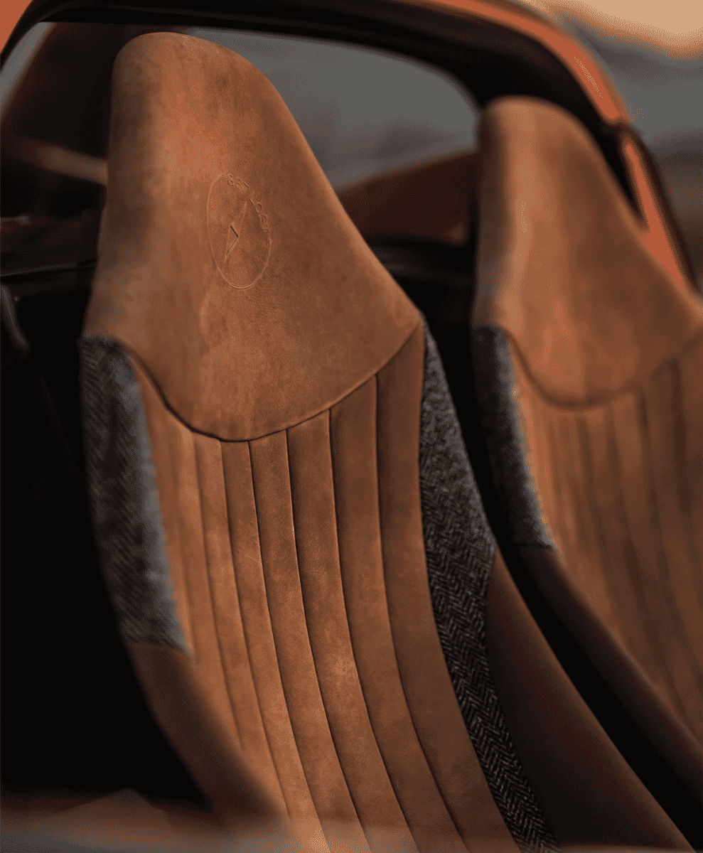 Detailed view of luxury tan suede car seats with herringbone wool inserts and embossed Get Lost logo.