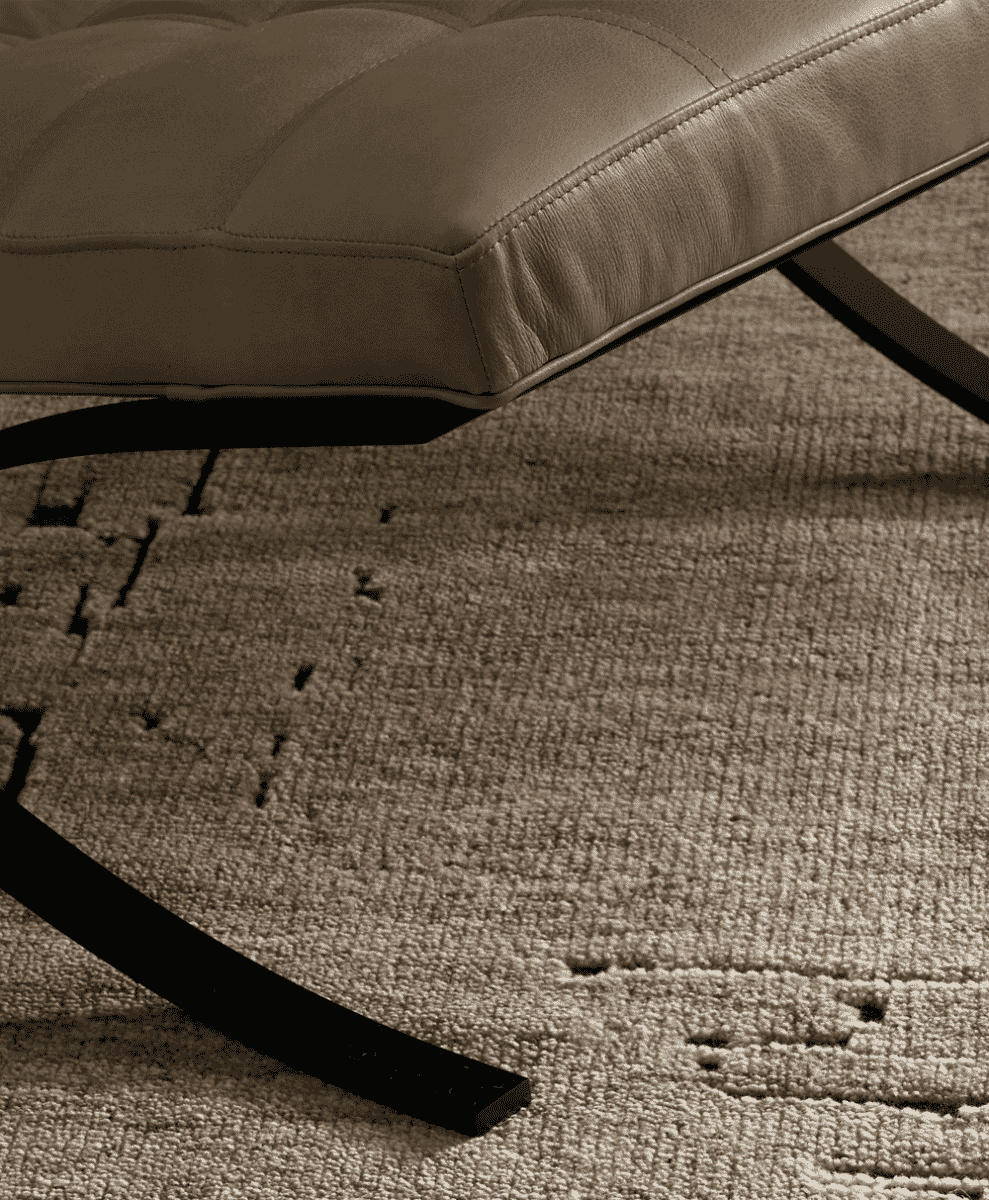 Close-up of a modern leather ottoman on a textured beige rug.
