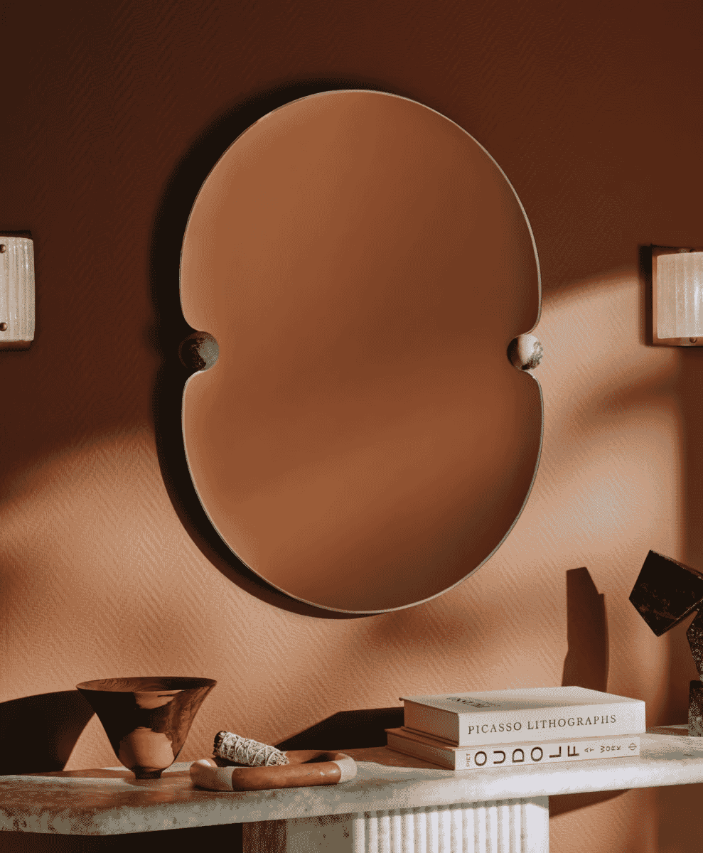 Lucetta mirror with scalloped edges above a marble console table.