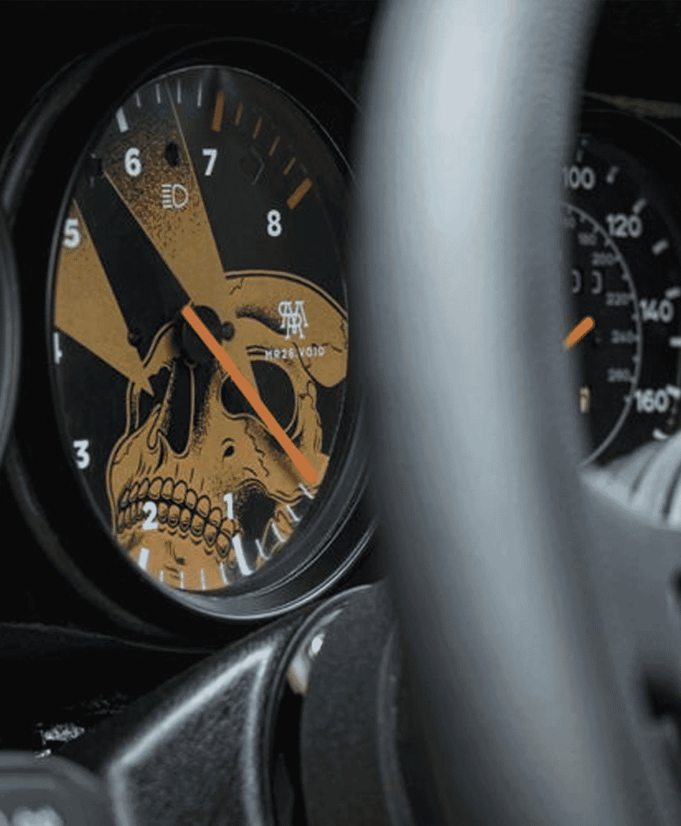 Close-up of a custom car dashboard with a skull-themed tachometer.