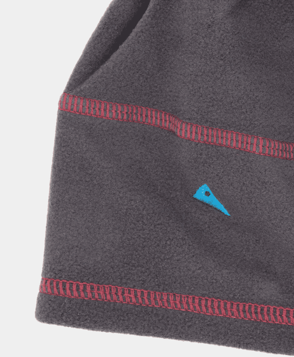 Close-up of the red stitching and logo on a gray fleece beanie.
