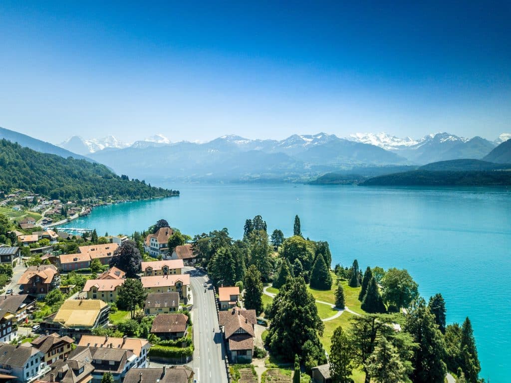 Aerial view of a lakeside town in Switzerland featuring traditional houses and mountain peaks.