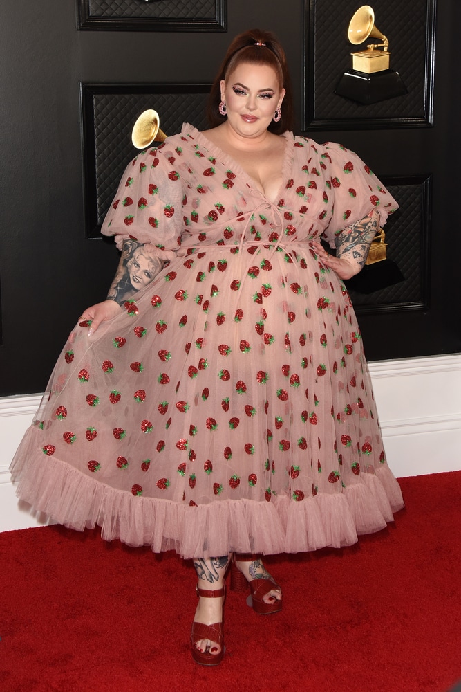 A woman in a blush-pink tulle 'strawberry dress' with glittery appliqués and puffed sleeves.