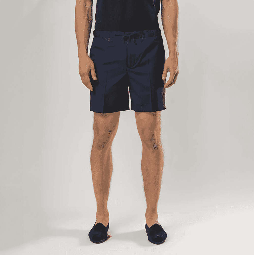 Male model wearing navy blue tailored shorts with a drawstring waist.