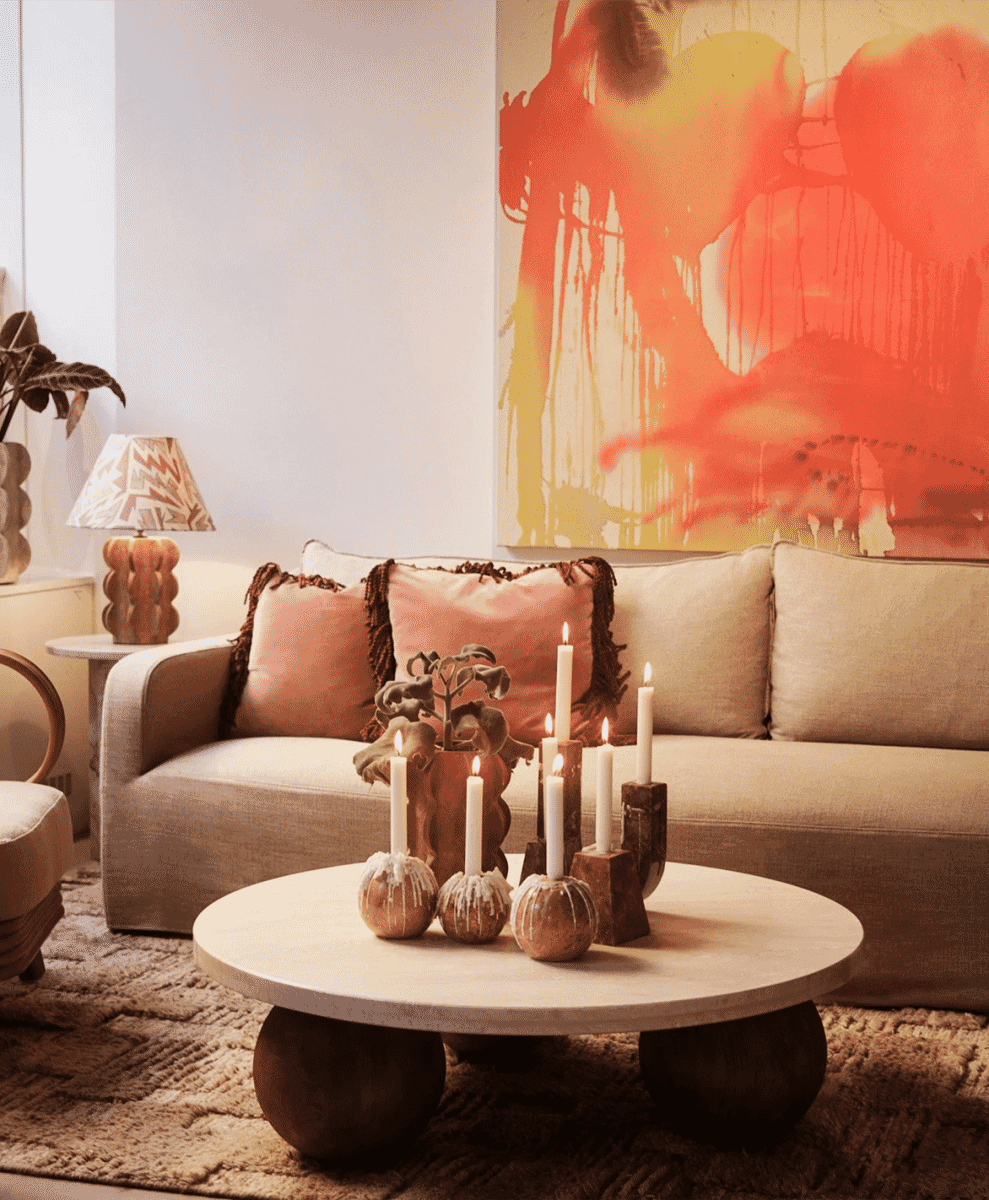 Bohemian-style living room with a beige sofa, textured pillows, and an orange abstract painting.