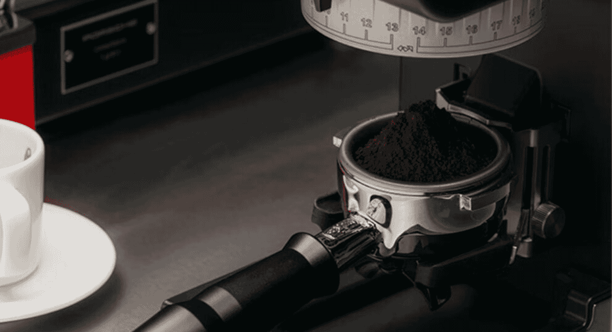 Close-up of a coffee grinder dispensing grounds into a portafilter.