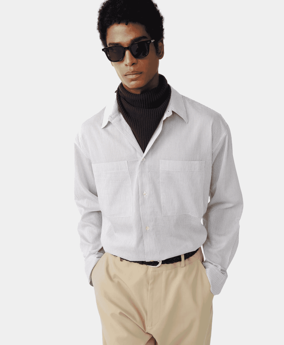 A man wearing a white pinstripe shirt over a black turtleneck.