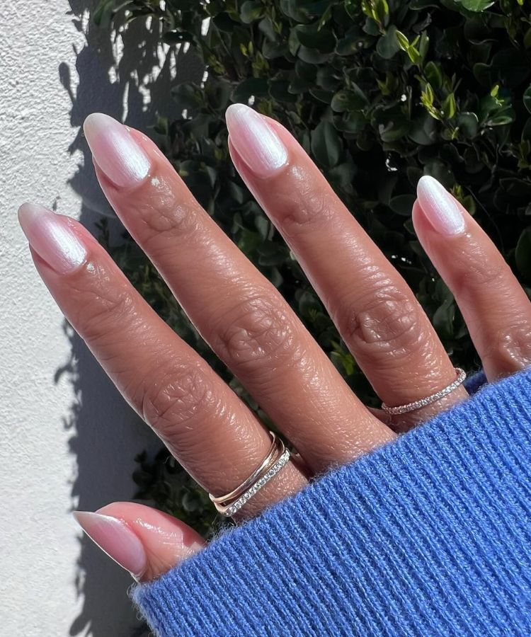 Nails with an iridescent pearl chrome finish reflecting soft light.