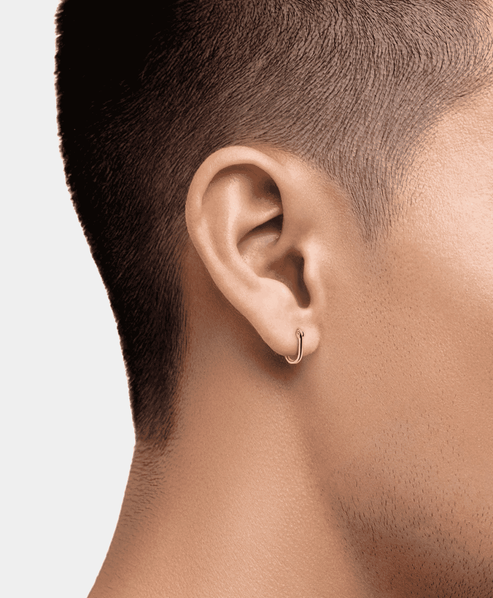 Side profile of a man wearing a small, sleek gold hoop earring.
