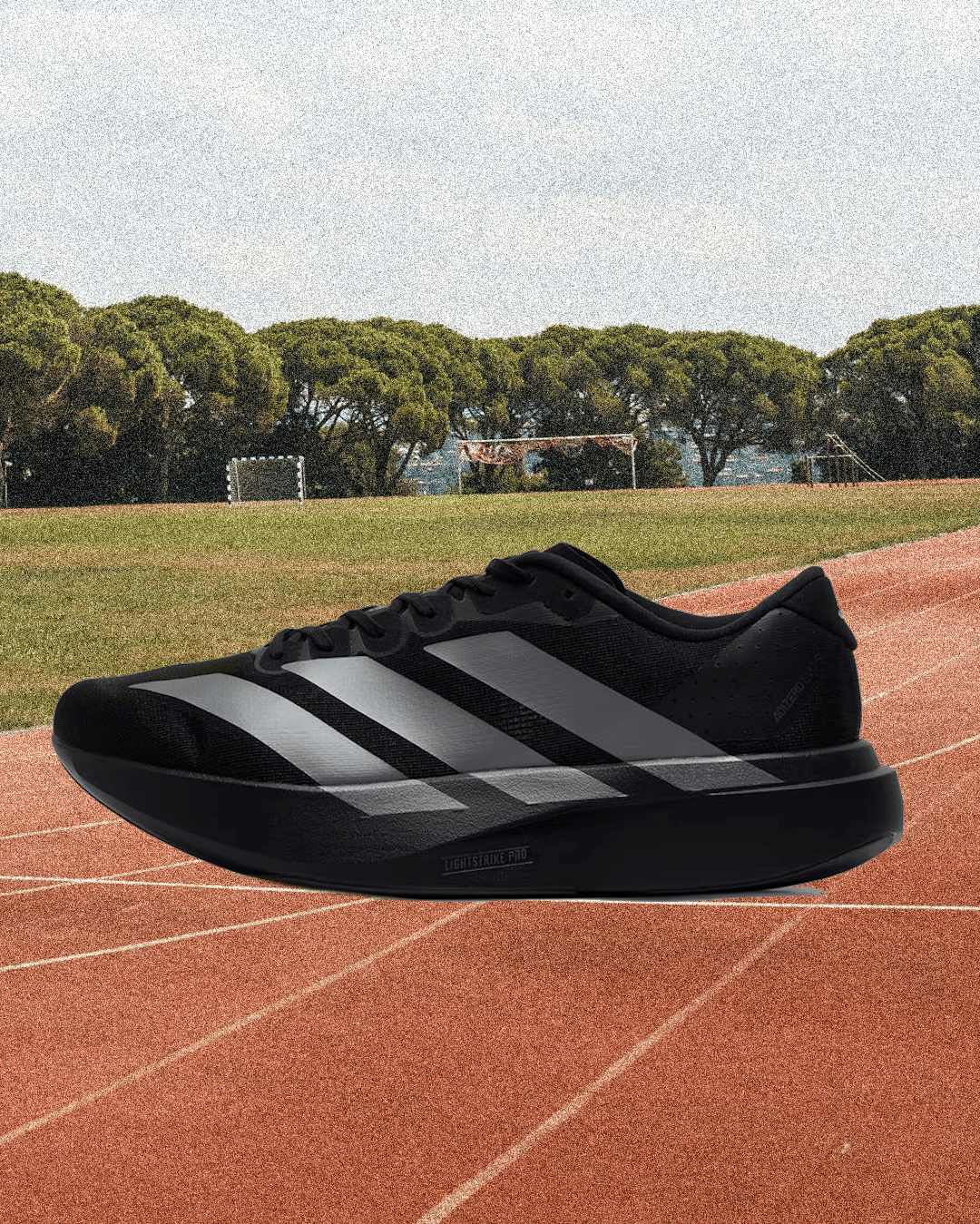 Close-up of a black Adidas Lightstrike Pro shoe with silver stripes on a red track.