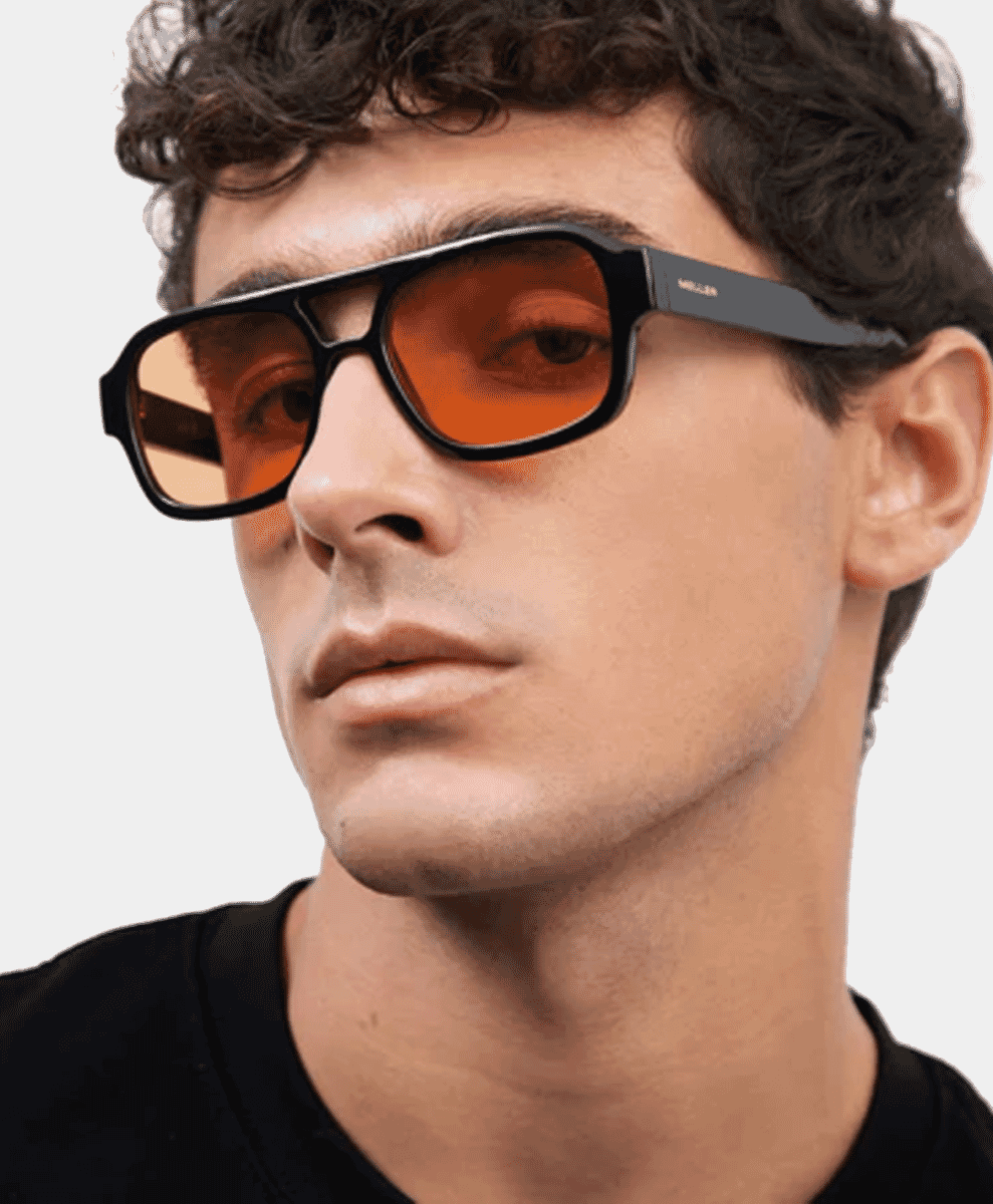 A man wearing bold black-framed sunglasses with orange-tinted lenses.