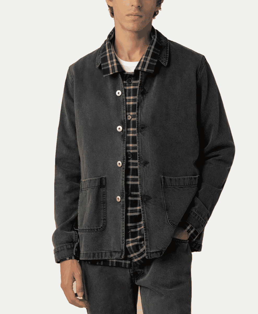 A man modeling a dark denim work jacket with a plaid shirt underneath.