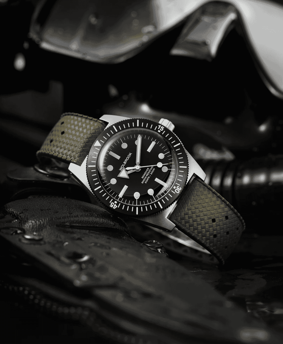 Black-and-white close-up of a Wolbrook diver watch on wet leather gear