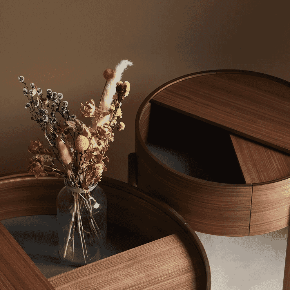 Two minimalist round wooden tables with a glass vase in soft lighting.