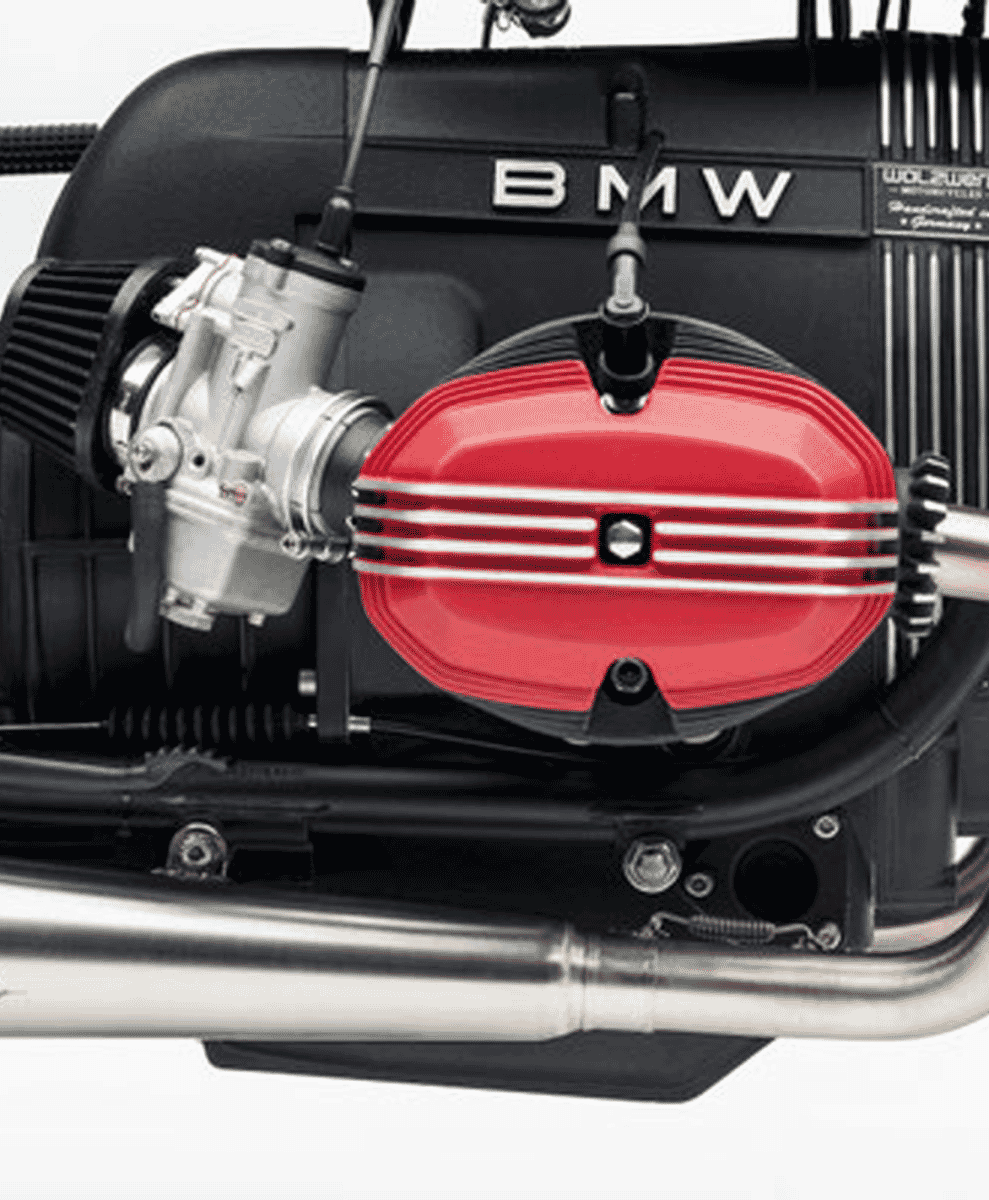 Close-up of a BMW motorcycle engine featuring a bright red valve cover and silver mechanical components.
