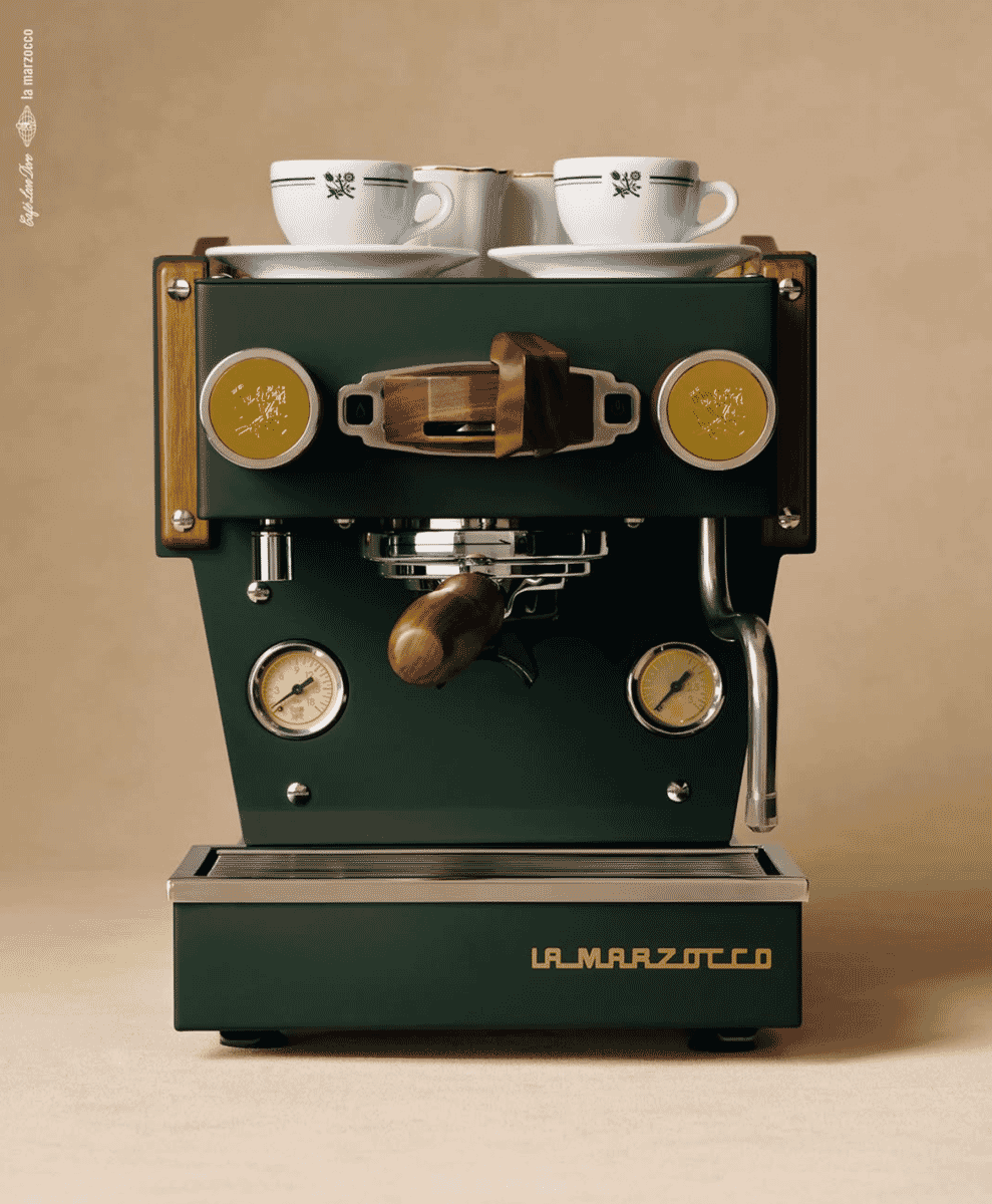 Close-up of a forest green La Marzocco Linea Micra espresso machine with wooden handles and floral ceramic cups.