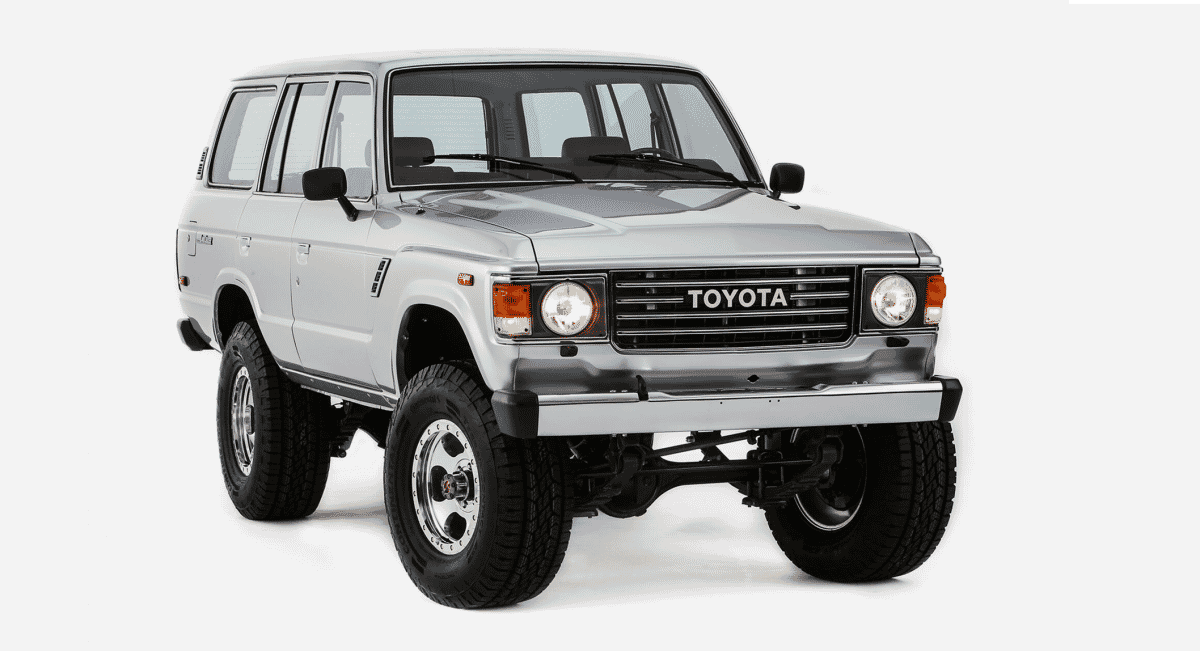 A silver Toyota Land Cruiser with lifted suspension and rugged tires in a studio setting.