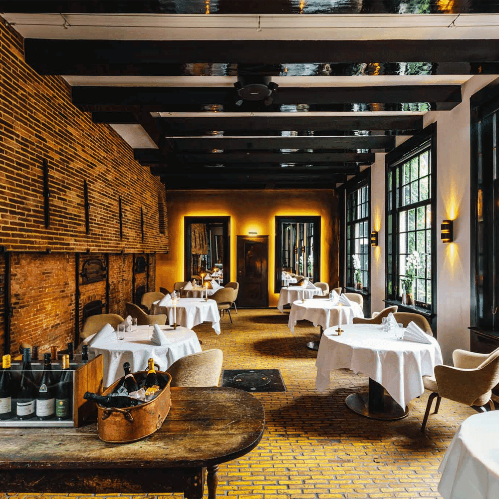 Elegant restaurant interior with historic brick walls and wooden beams.