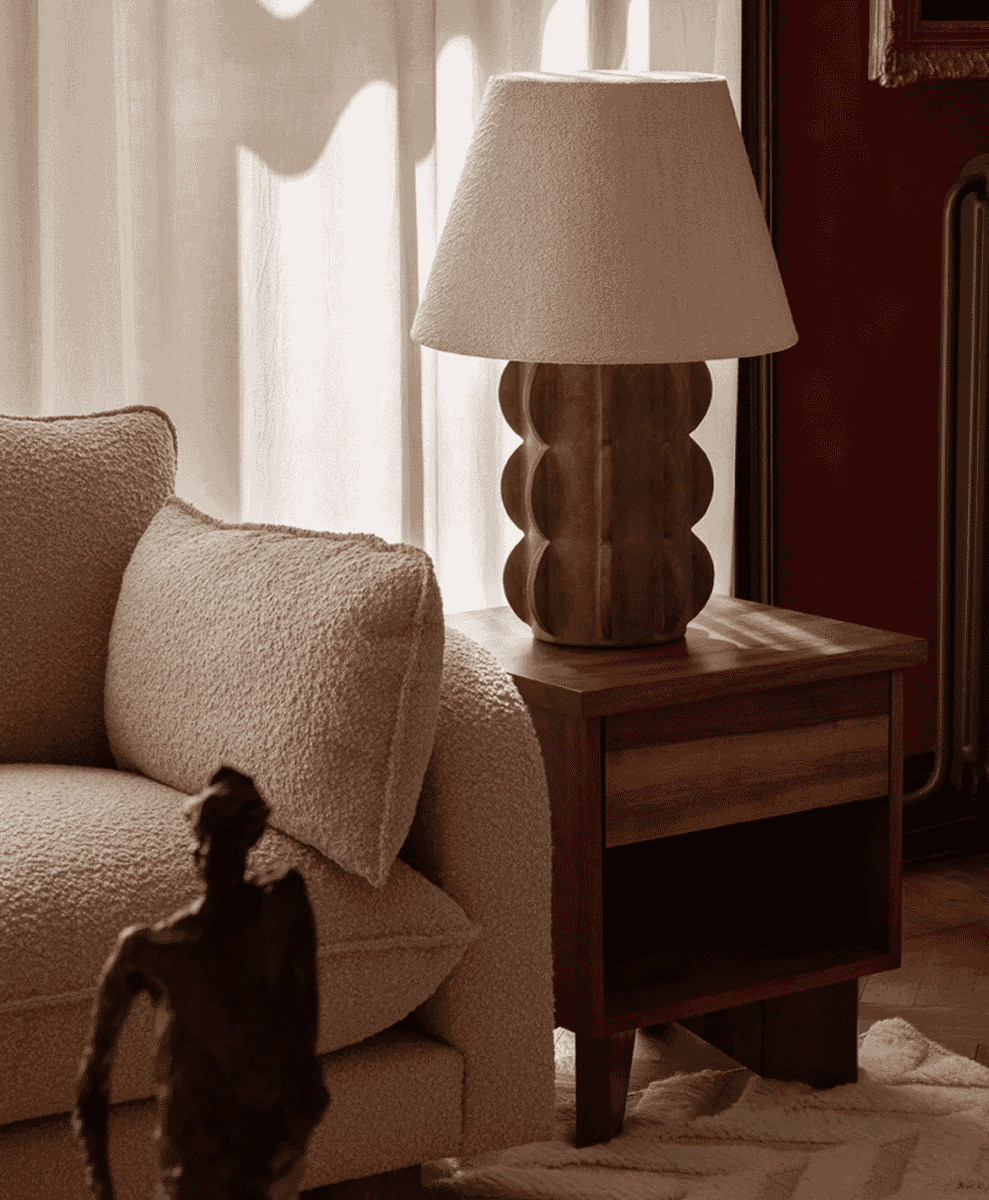 A sculptural brown table lamp on a side table in a cozy, naturally lit room.