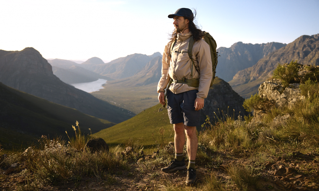 Hiker standing on a mountain trail overlooking a valley, wearing the full Fjällräven SS26 lightweight kit.