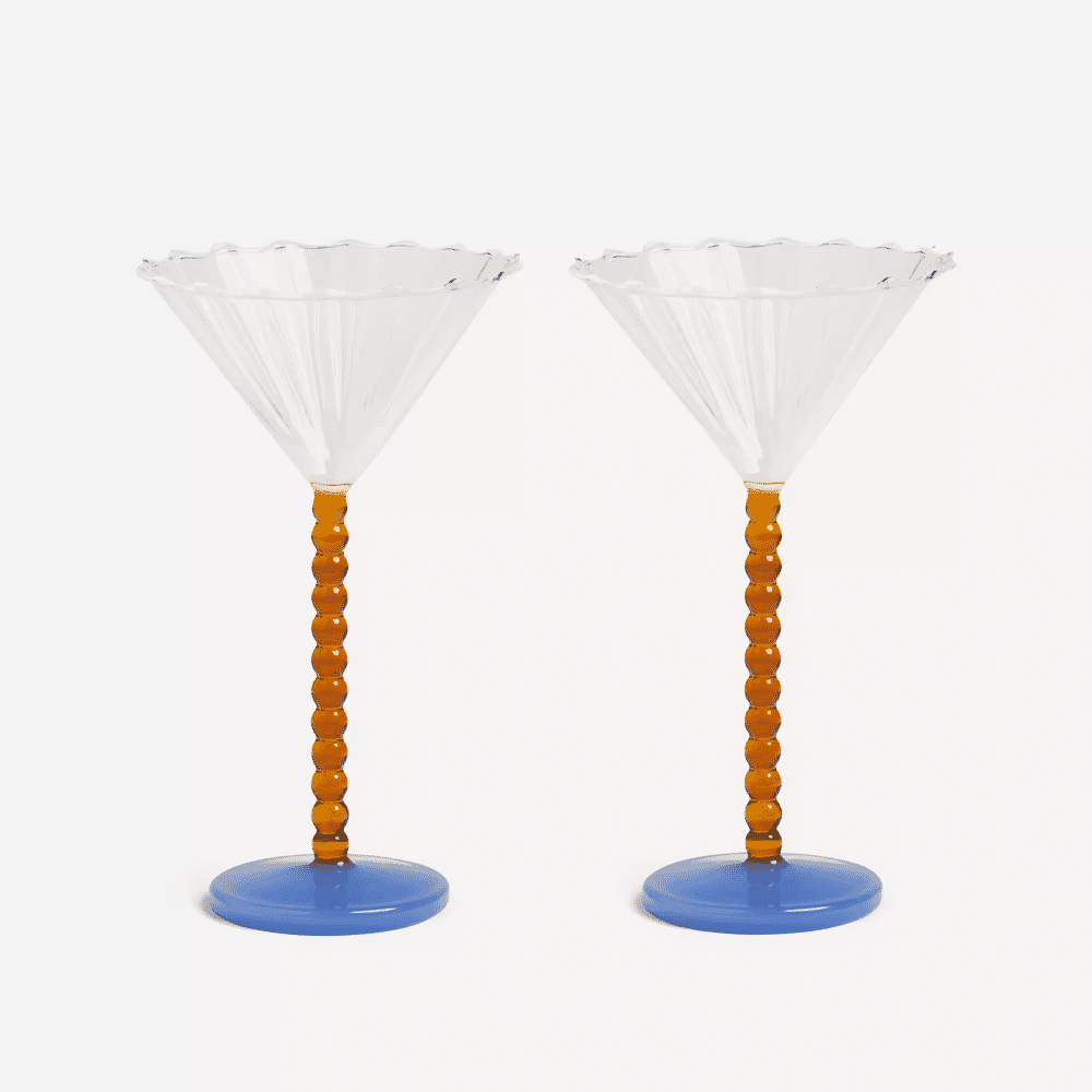 Two ornate cocktail glasses featuring blue bases and amber beaded stems with scalloped rims.