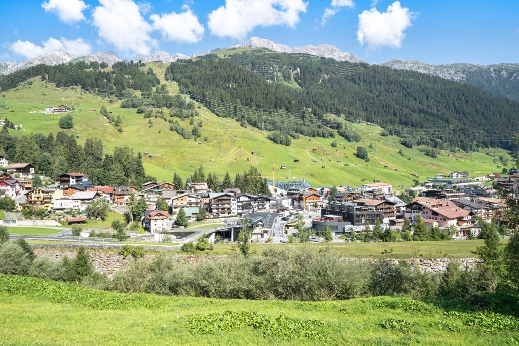 Traditional chalet-style buildings nestled in green hills under a blue sky.
