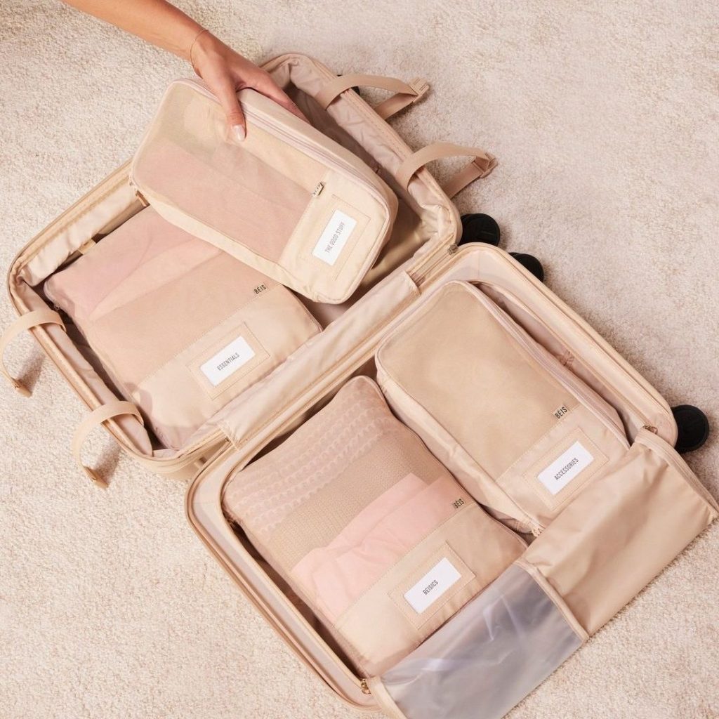 Close-up of premium beige Béis luggage and travel accessories in a bright setting.