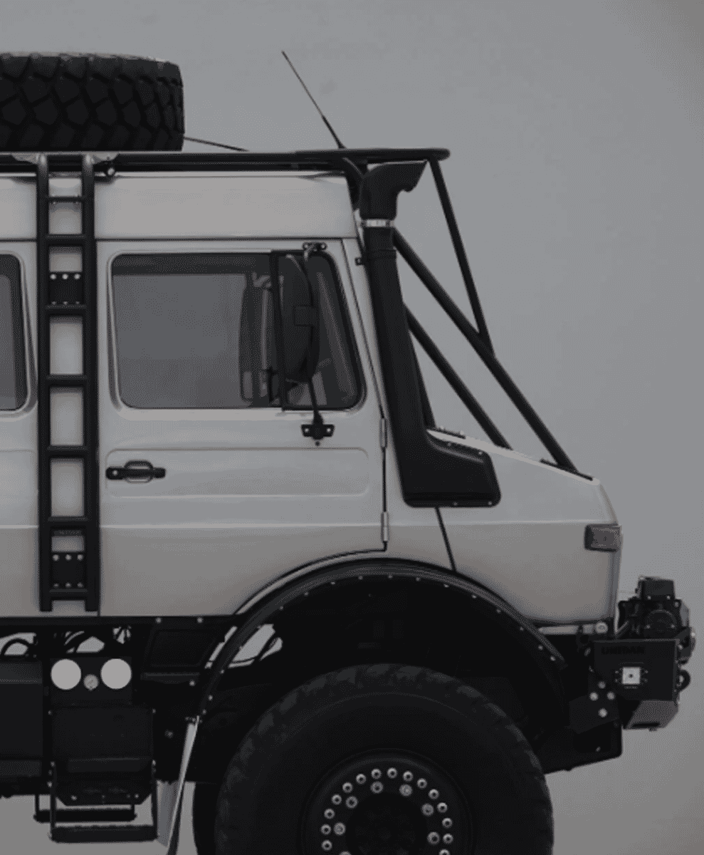 Profile shot of the white off-road truck highlighting the black technical accessories and utilitarian build.