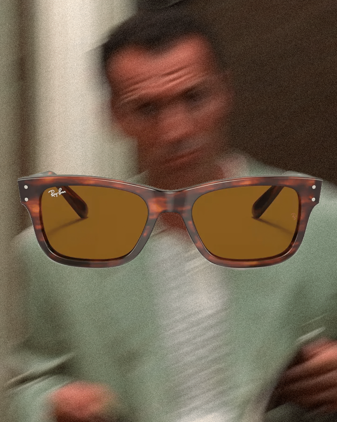Man in a light green sweater with tortoiseshell Ray-Ban sunglasses in the foreground.