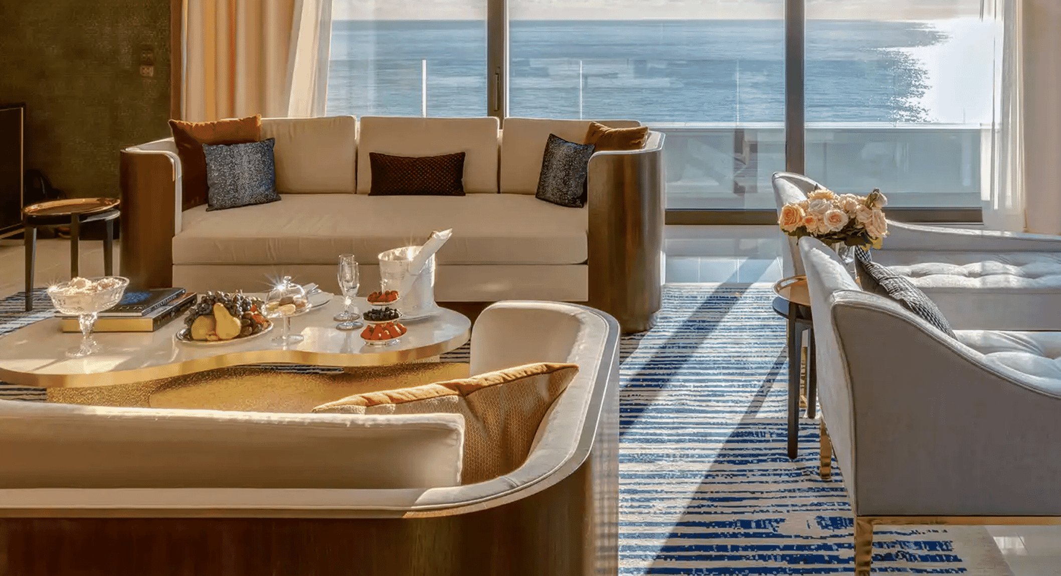 Luxury living room with cream sofas and a scenic ocean view through large windows.