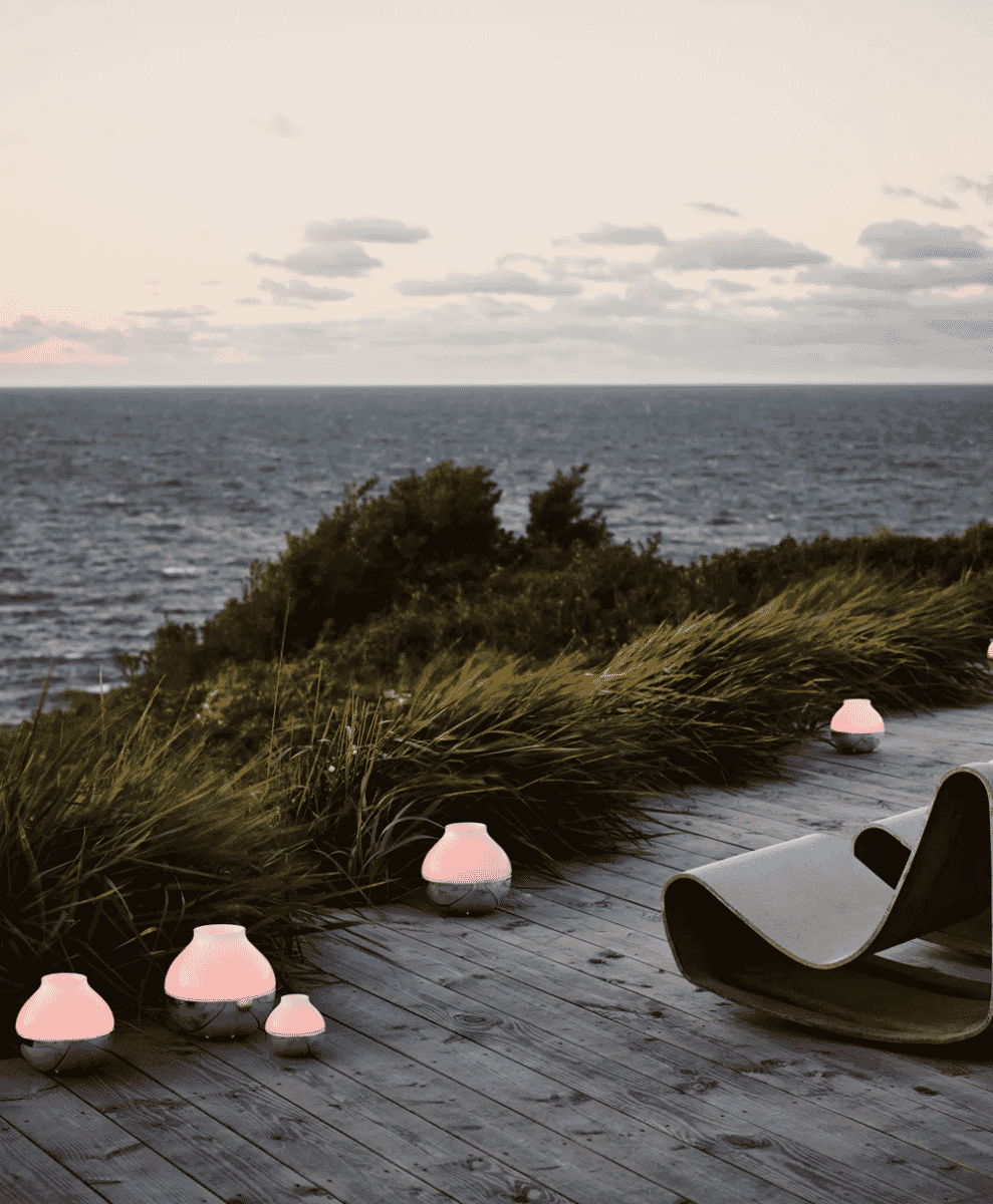 A serene seaside deck at dusk with modern glowing lanterns overlooking the ocean.