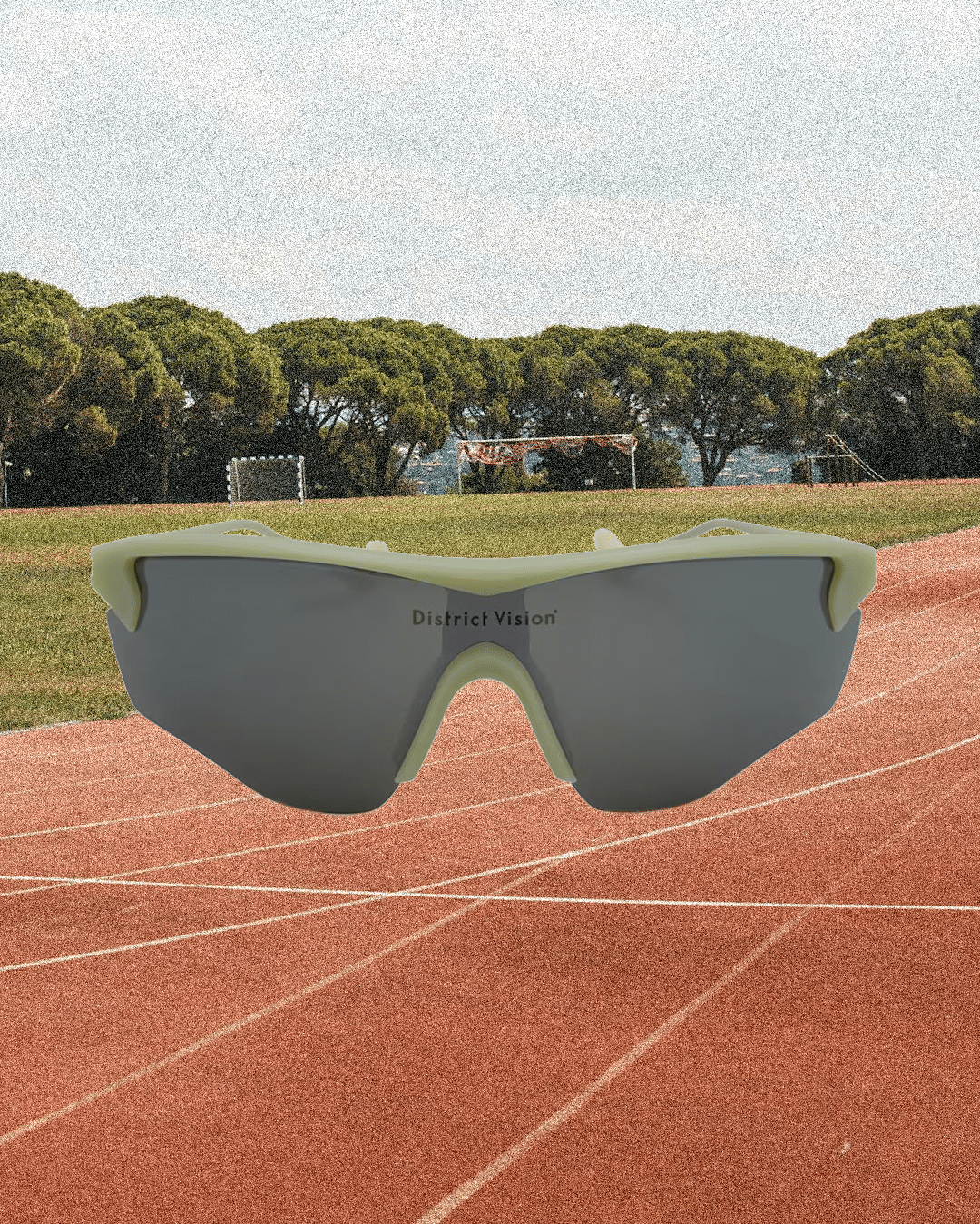 Reflective District Vision sunglasses displayed over a running track.