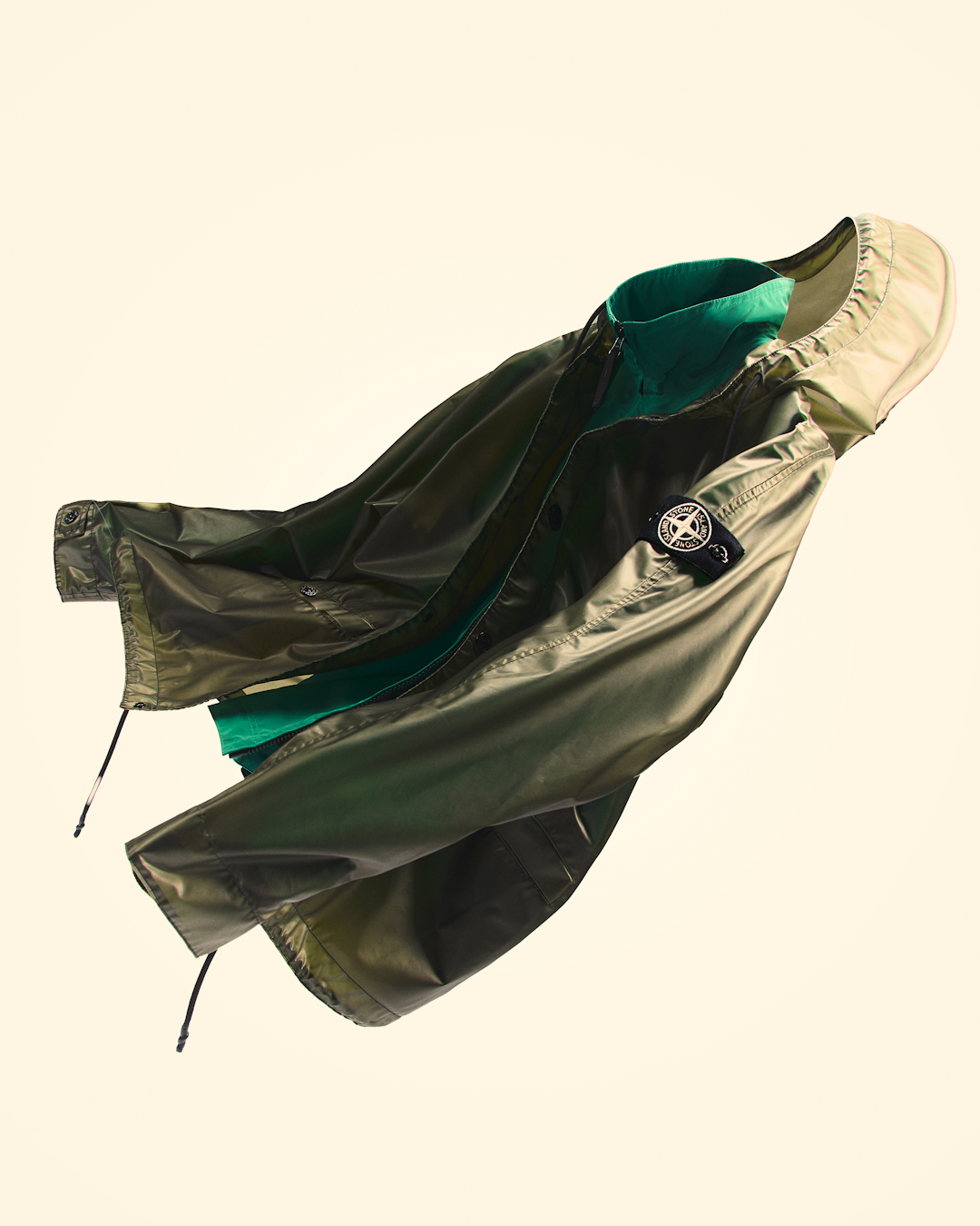 Dynamic shot of the olive green Stone Island jacket showcasing its reflective and glossy properties.