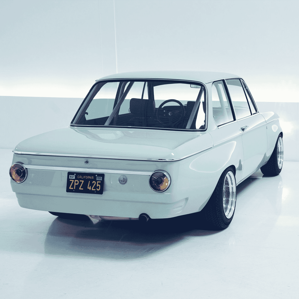 White vintage BMW 2002 with California license plate ZPZ 425 and custom black wheels.
