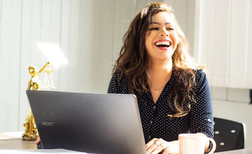 A woman wearing a dark blue polka-dot blouse looking confident and approachable in an office environment.
