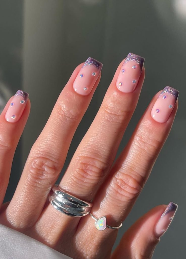 Nail art featuring 3D gem embellishments and metallic edges.