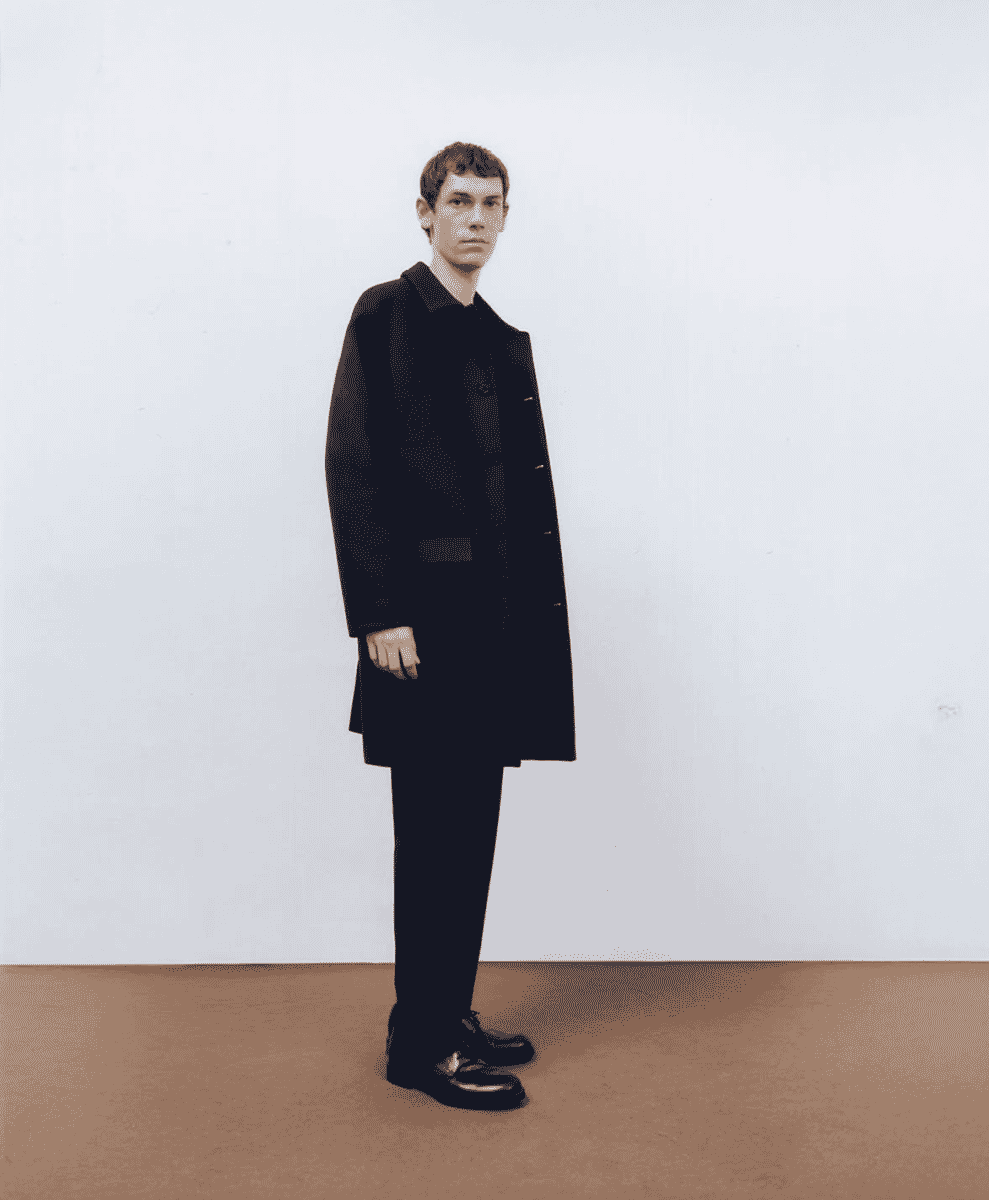 Full-body shot of a man in a black tailored wool overcoat.