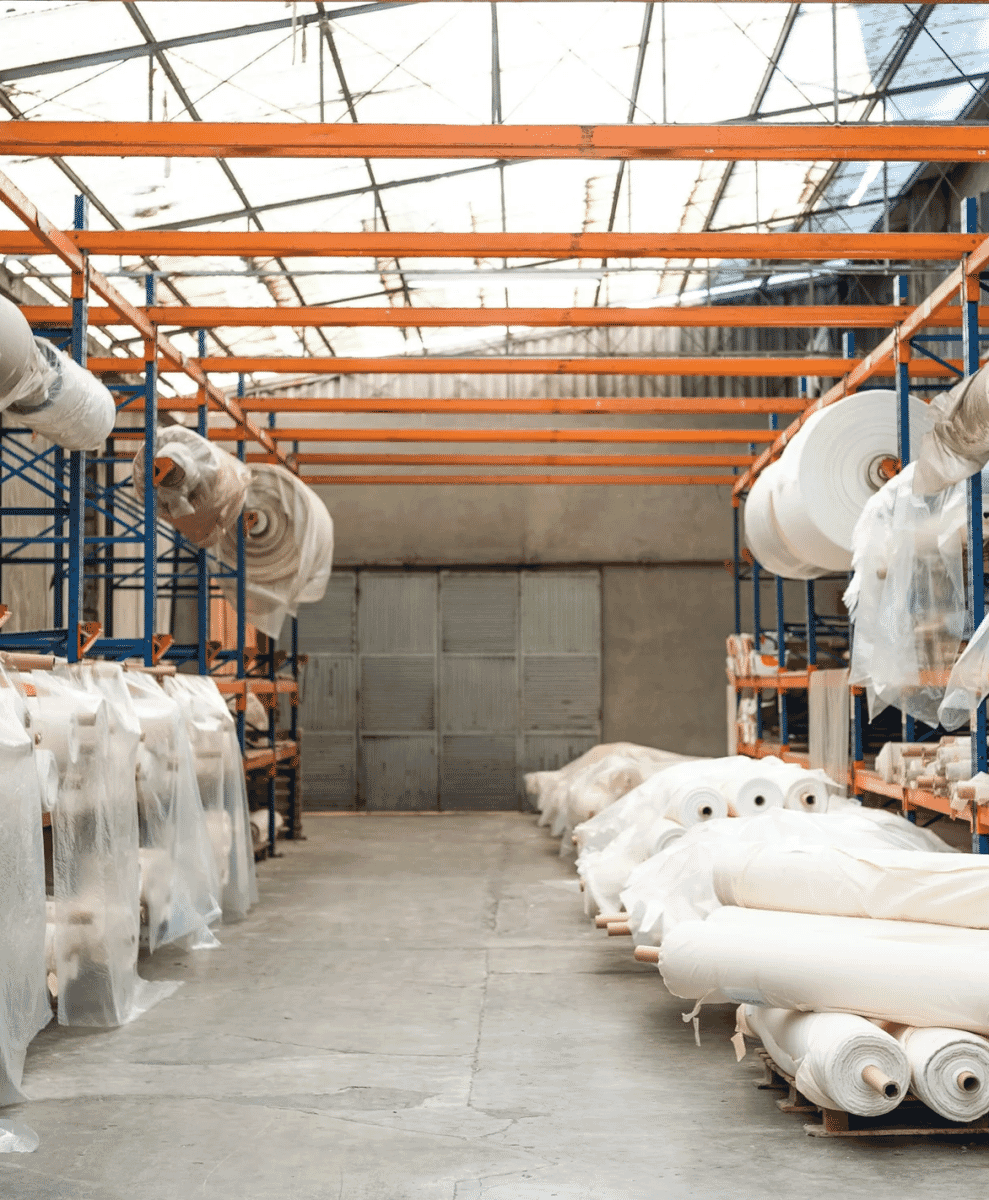 Large industrial warehouse with rolls of high-quality white fabric stored on tall shelves
