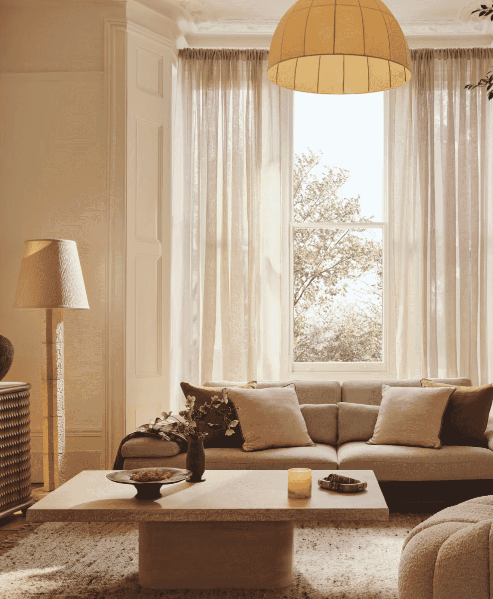 Close-up of beige modular sofa with textured linen cushions under warm lighting.