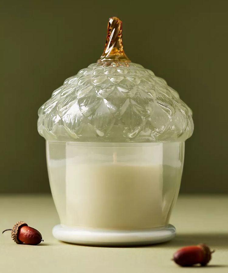Glass acorn-shaped cloche candle with woody leather and leaves scent.