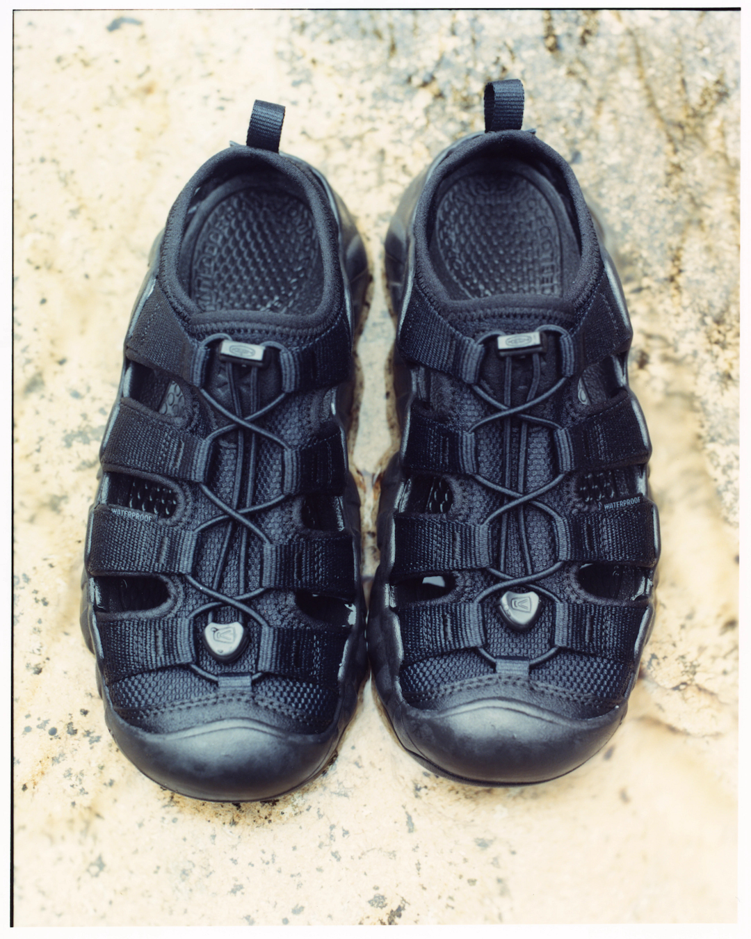 Action shot of the Hyperport sandals on wet rocks near a water source, showing the outsole grip.