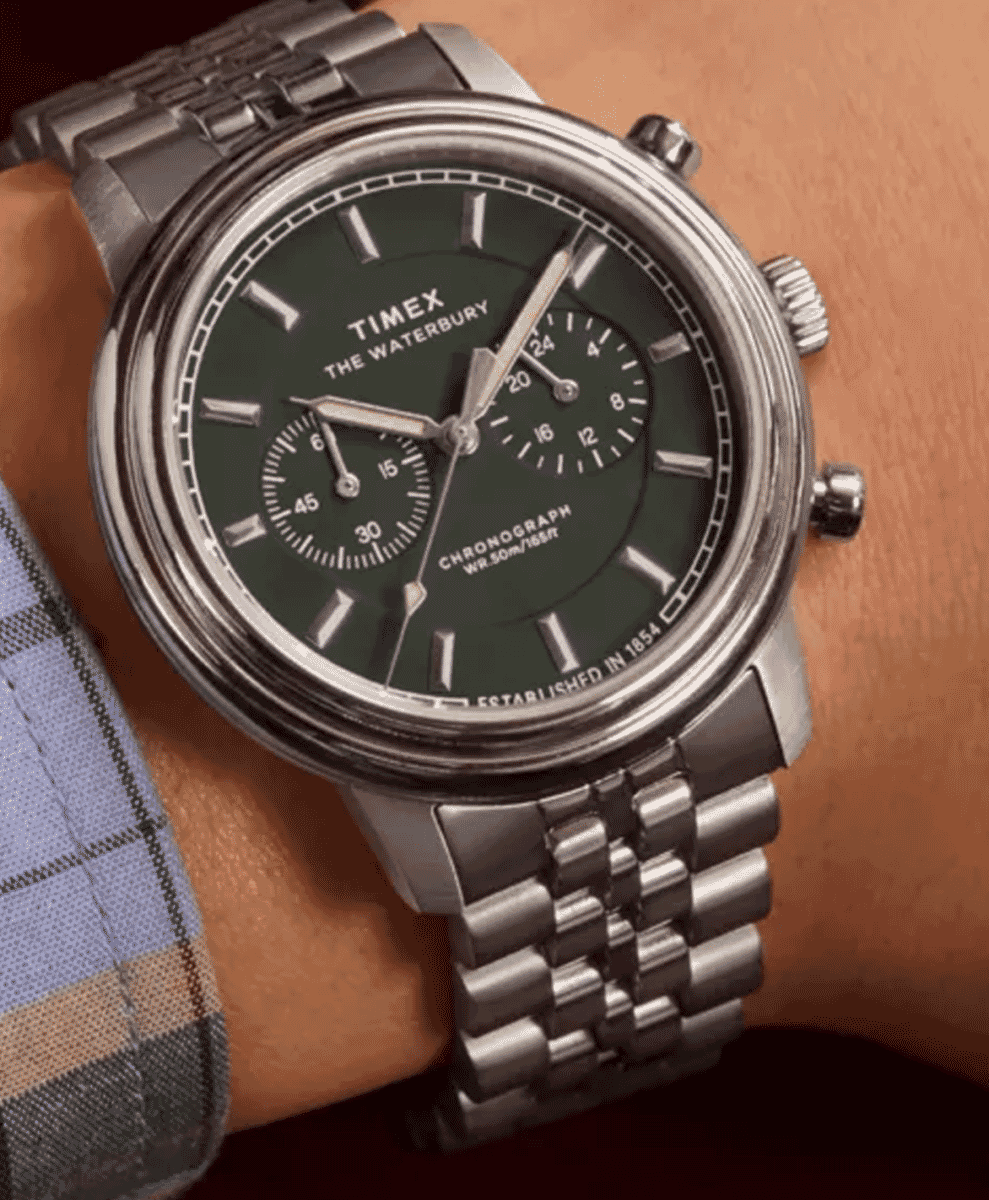 Close-up of a silver Timex Waterbury chronograph watch with a green dial on a man's wrist.