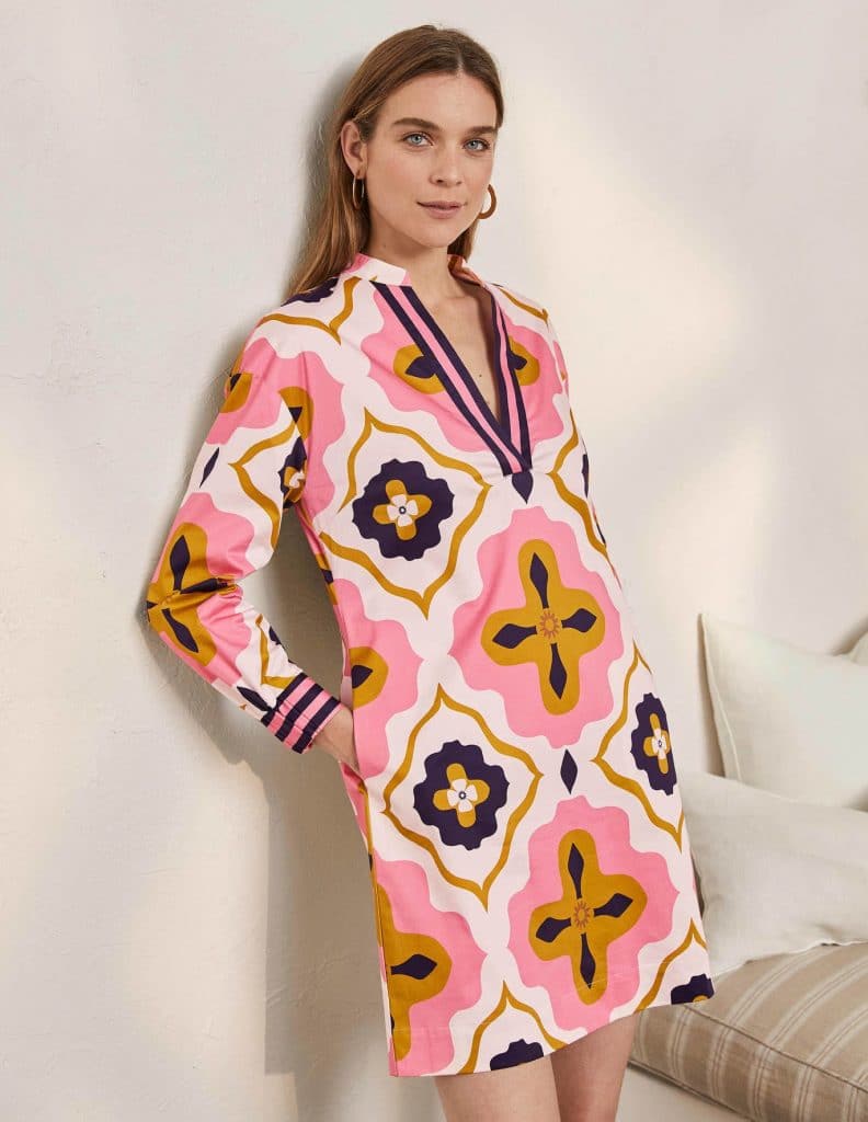 Woman in a vibrant navy, pink, and gold patterned tunic dress.