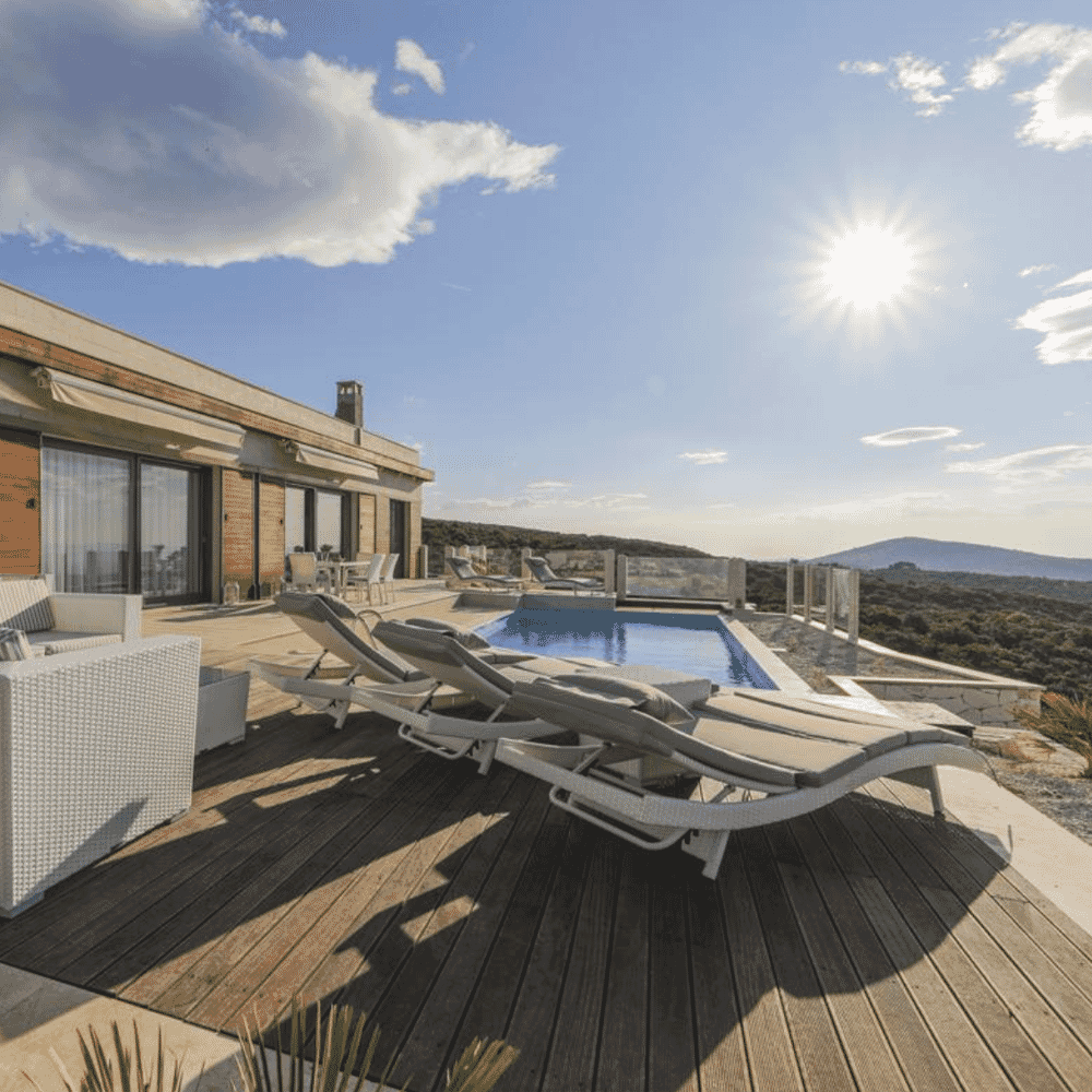 A sunlit luxury terrace with modern lounge furniture overlooking desert hills.