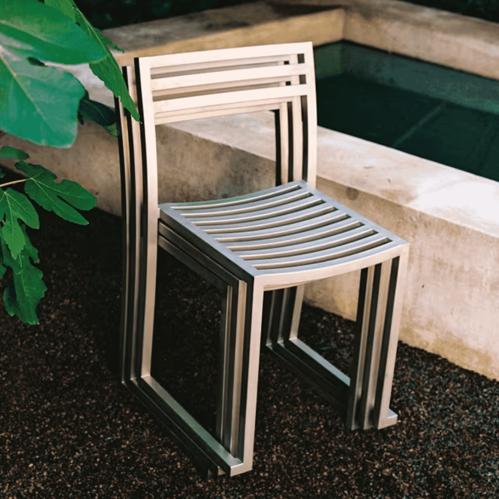 A stack of minimalist black metal chairs positioned on a concrete poolside deck.