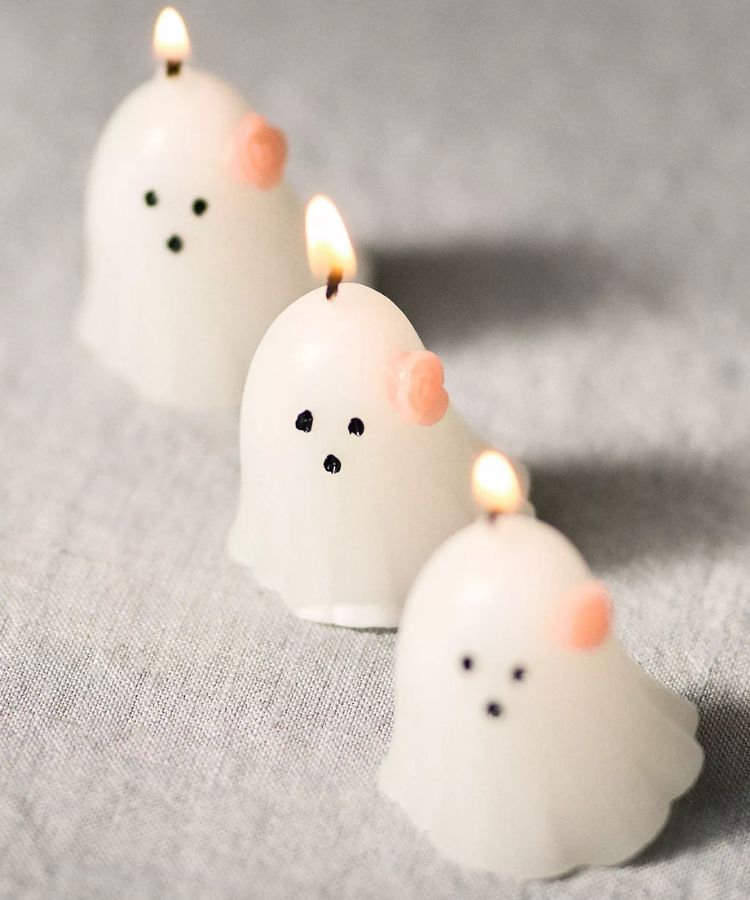 A set of four white ghost-shaped decorative wax candles.