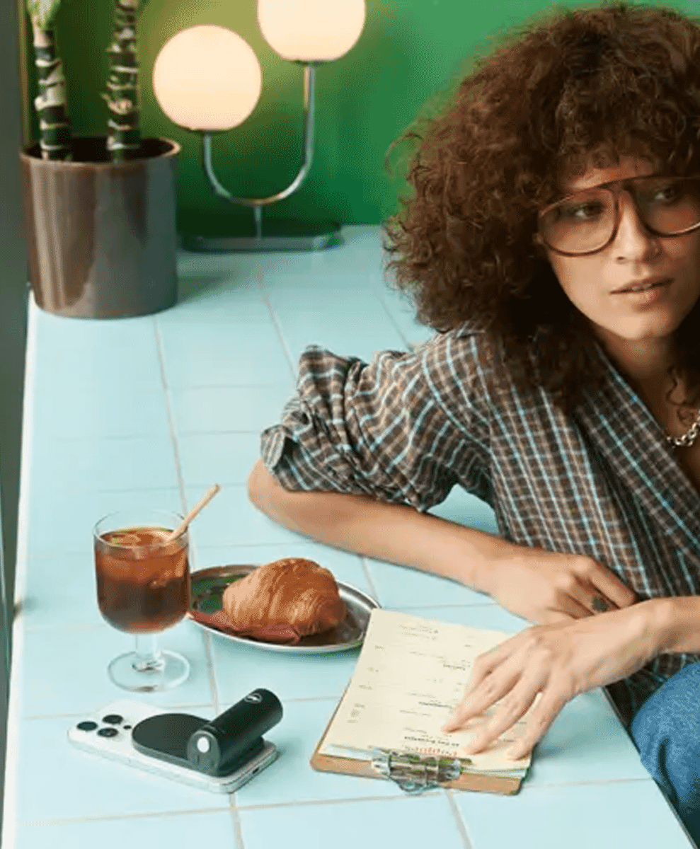 A woman in a plaid shirt enjoying coffee and a croissant at a café, representing the lifestyle aspect of Leica photography.