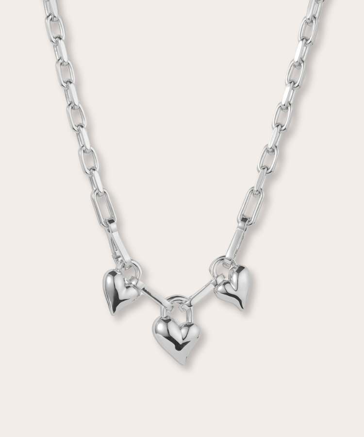 A gold necklace featuring three heart-shaped pendants.
