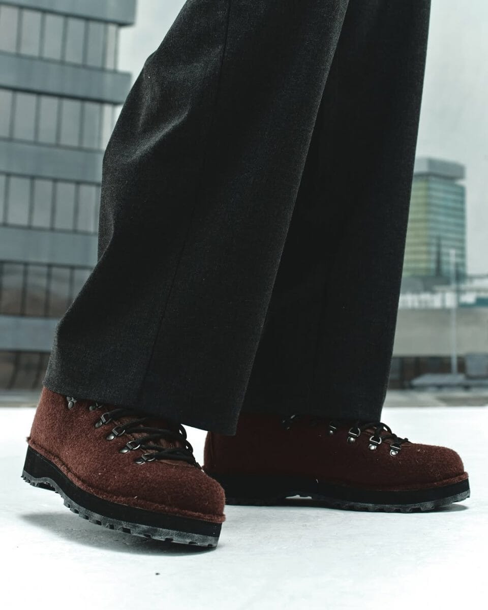 Close-up of rugged brown suede hiking boots paired with dark wide-leg trousers.